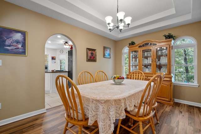 dining area with arched walkways, wood finished floors, an inviting chandelier, and baseboards