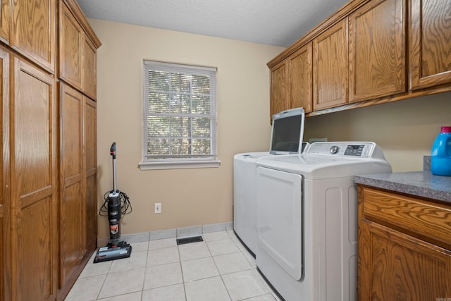 clothes washing area featuring light tile patterned floors, washing machine and dryer, and cabinet space
