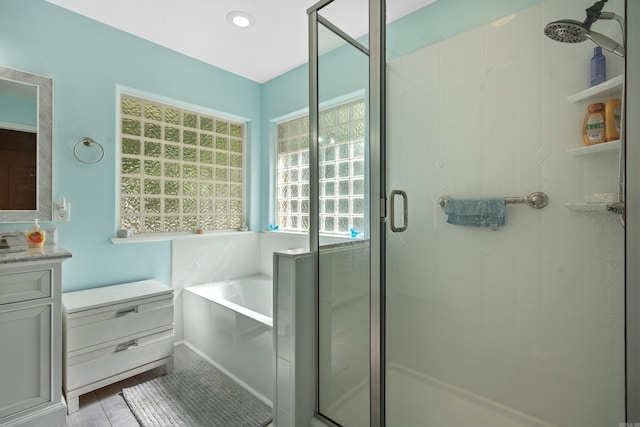 bathroom featuring a shower stall, a bath, and vanity
