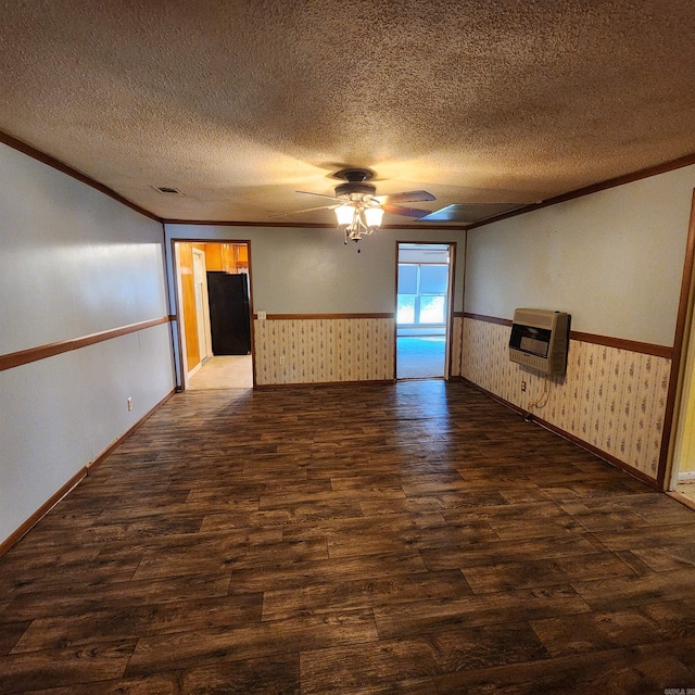 empty room featuring ceiling fan, ornamental molding, heating unit, a textured ceiling, and dark hardwood / wood-style flooring