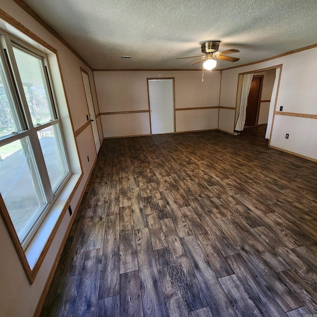 spare room featuring a textured ceiling, a healthy amount of sunlight, ceiling fan, and dark wood-type flooring