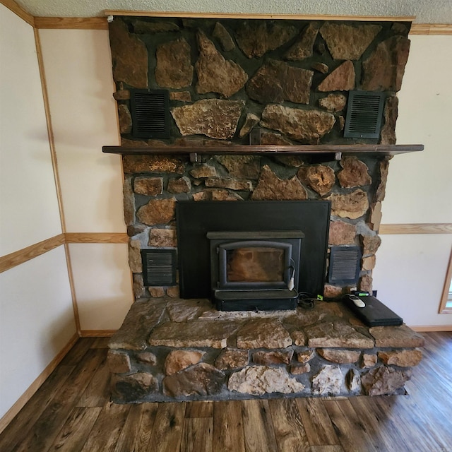 room details featuring a textured ceiling, crown molding, hardwood / wood-style floors, and a wood stove