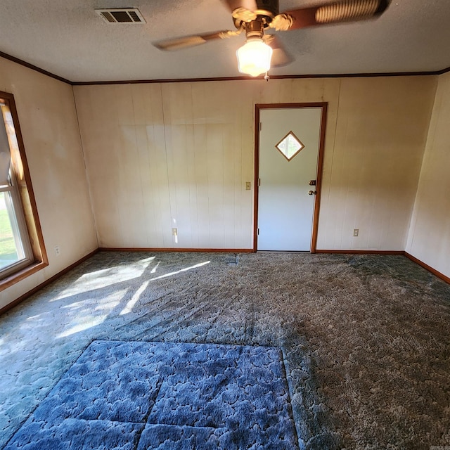 interior space featuring a textured ceiling, carpet flooring, ornamental molding, and ceiling fan