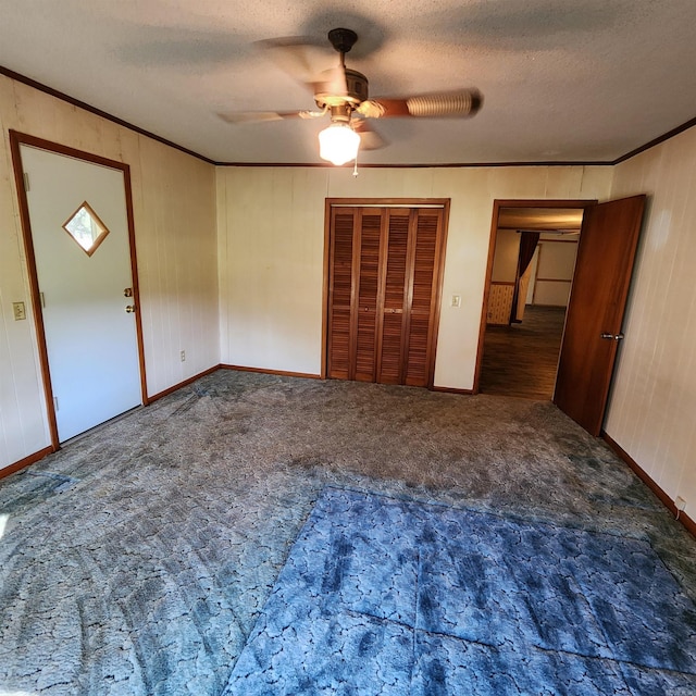 unfurnished bedroom featuring a textured ceiling, ornamental molding, dark colored carpet, and ceiling fan