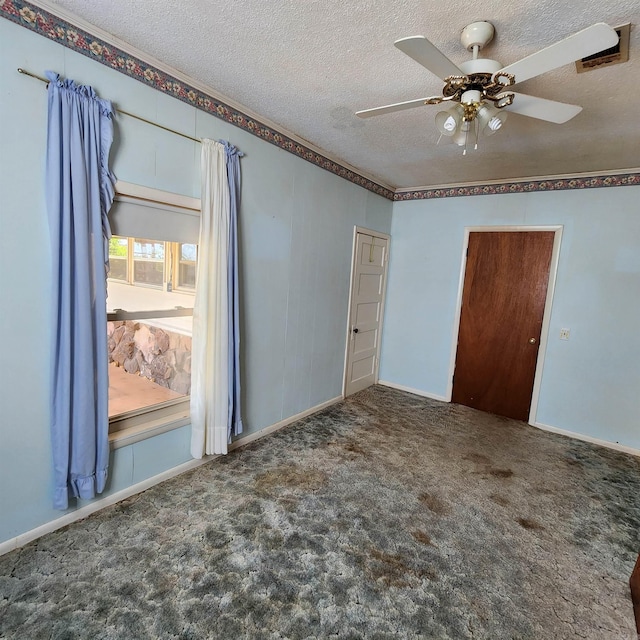 empty room featuring dark colored carpet, ceiling fan, and a textured ceiling