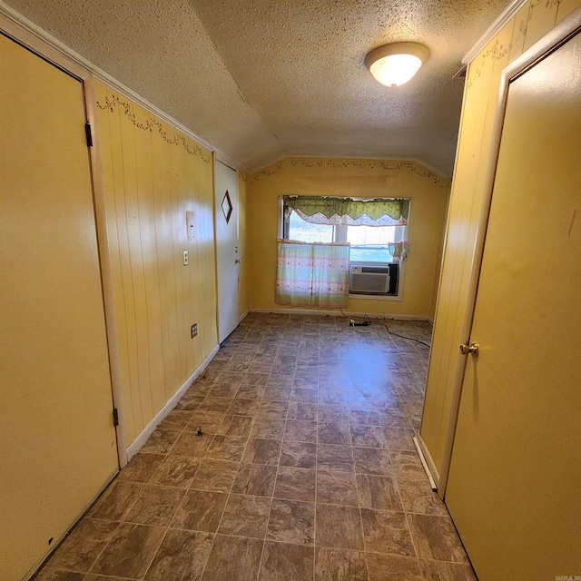 interior space with a textured ceiling, cooling unit, lofted ceiling, and wood walls