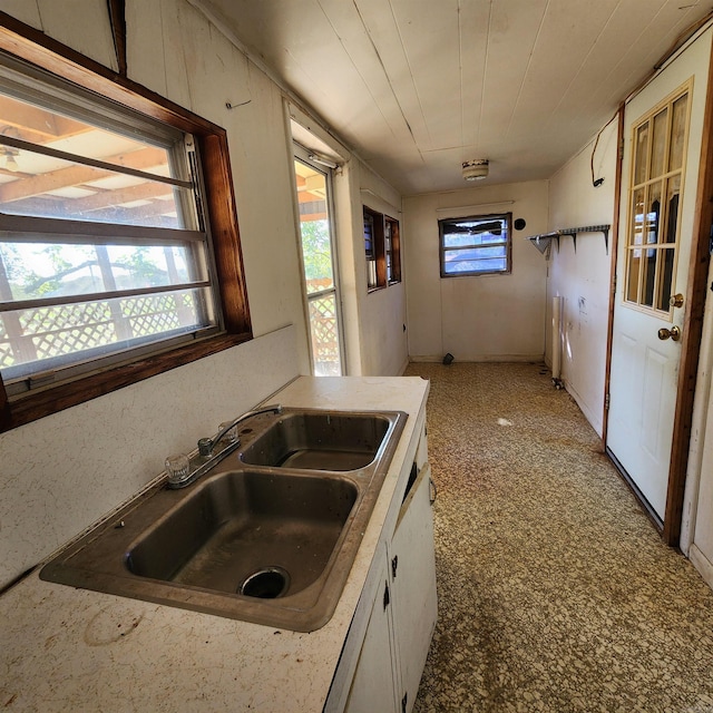 kitchen featuring wood ceiling, white cabinetry, and sink