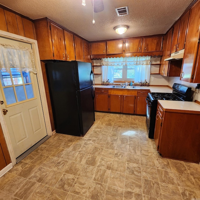 kitchen featuring a textured ceiling, black appliances, and sink