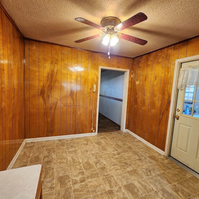 empty room featuring wooden walls, a textured ceiling, and ceiling fan