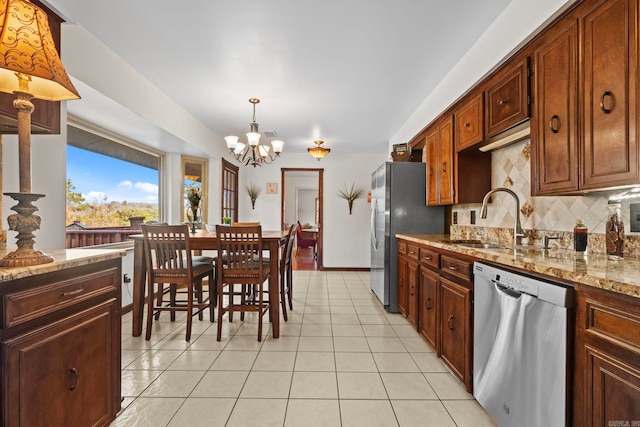 kitchen with sink, decorative backsplash, appliances with stainless steel finishes, decorative light fixtures, and light stone countertops