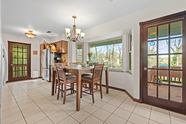 dining area featuring an inviting chandelier, light tile patterned floors, and a wealth of natural light