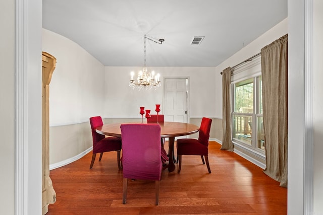 dining space with wood-type flooring and a chandelier