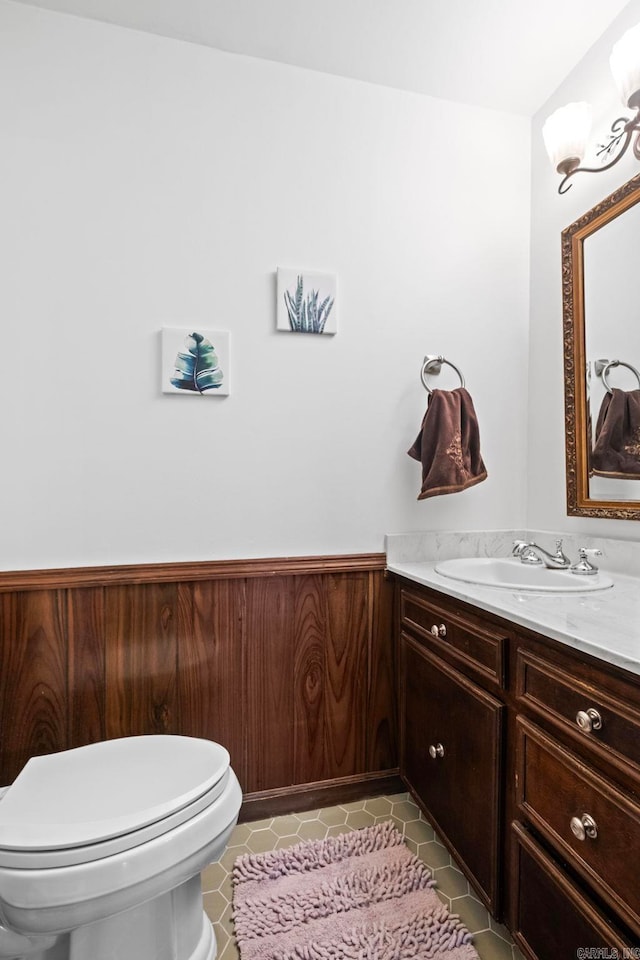 bathroom with vanity, wood walls, toilet, and tile patterned flooring