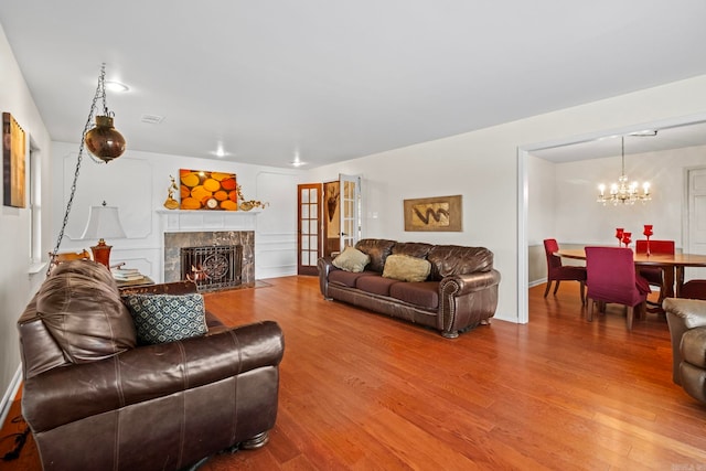 living room featuring an inviting chandelier, wood-type flooring, and a tile fireplace