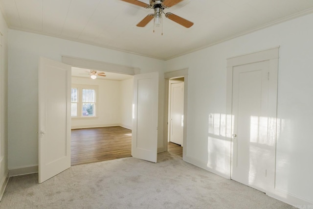 carpeted spare room featuring ceiling fan and crown molding