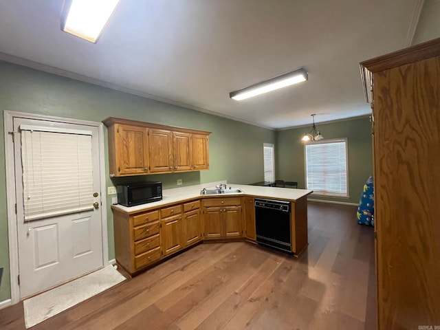 kitchen with hanging light fixtures, black appliances, crown molding, hardwood / wood-style flooring, and sink