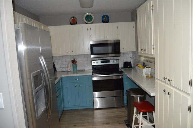 kitchen featuring decorative backsplash, white cabinetry, blue cabinetry, stainless steel appliances, and dark hardwood / wood-style floors