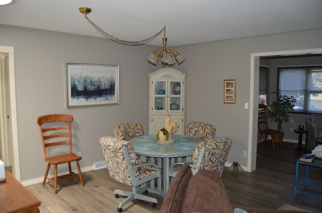 dining room with an inviting chandelier, a textured ceiling, and hardwood / wood-style floors