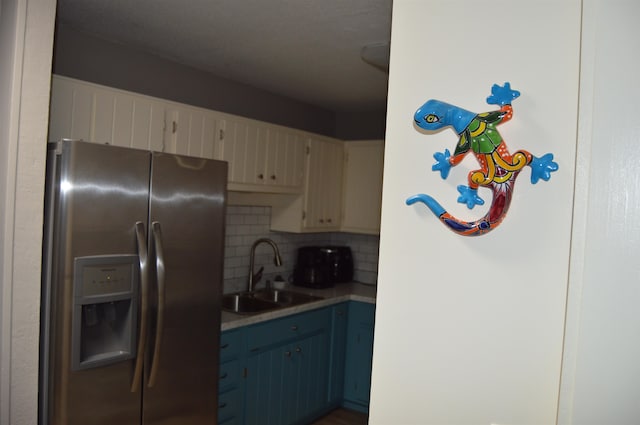 kitchen with decorative backsplash, blue cabinets, stainless steel fridge with ice dispenser, and sink