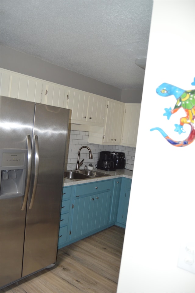 kitchen with tasteful backsplash, stainless steel fridge with ice dispenser, sink, white cabinetry, and light hardwood / wood-style flooring