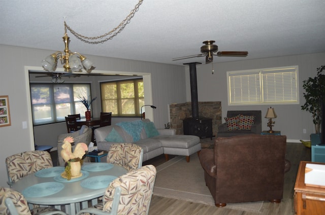 living room with a notable chandelier, light wood-type flooring, a textured ceiling, and a wood stove