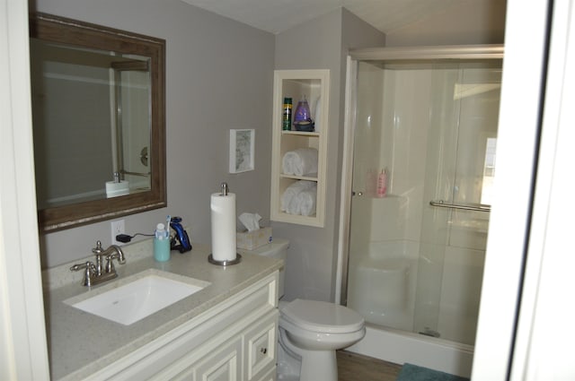 bathroom with hardwood / wood-style flooring, vanity, toilet, and a shower with shower door