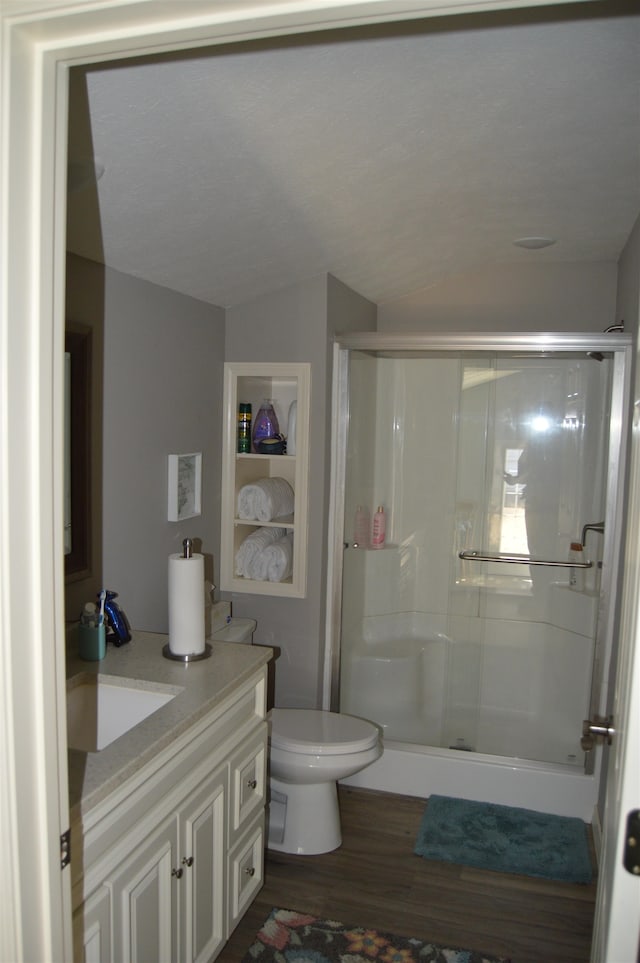 bathroom featuring wood-type flooring, vanity, a shower with shower door, and toilet