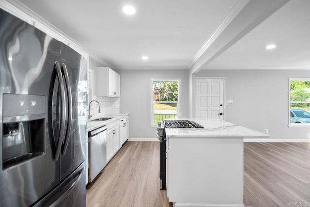 kitchen featuring appliances with stainless steel finishes, a healthy amount of sunlight, sink, and white cabinets