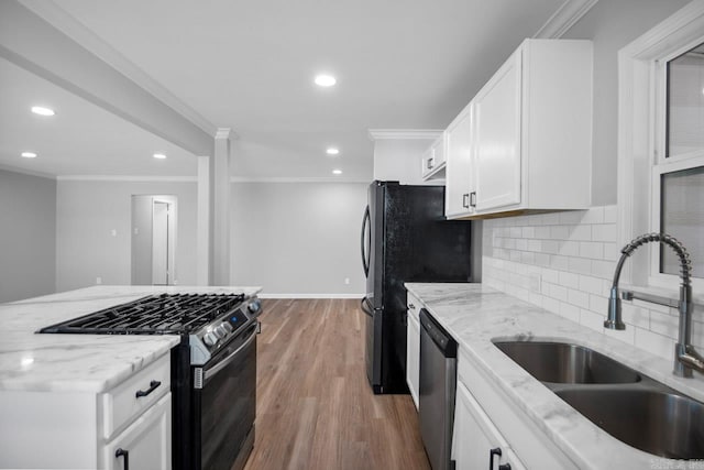 kitchen featuring appliances with stainless steel finishes, light hardwood / wood-style floors, white cabinets, light stone countertops, and sink