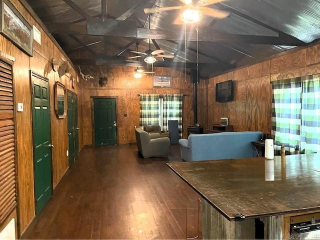 unfurnished dining area featuring vaulted ceiling with beams, wood walls, dark hardwood / wood-style flooring, and a wood stove