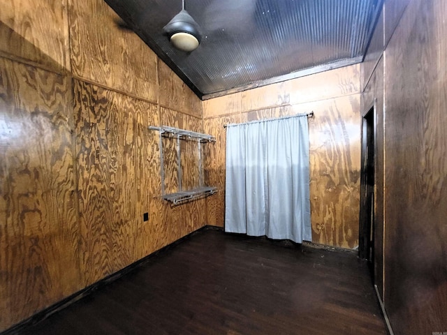 spare room with dark hardwood / wood-style flooring, wooden walls, and vaulted ceiling