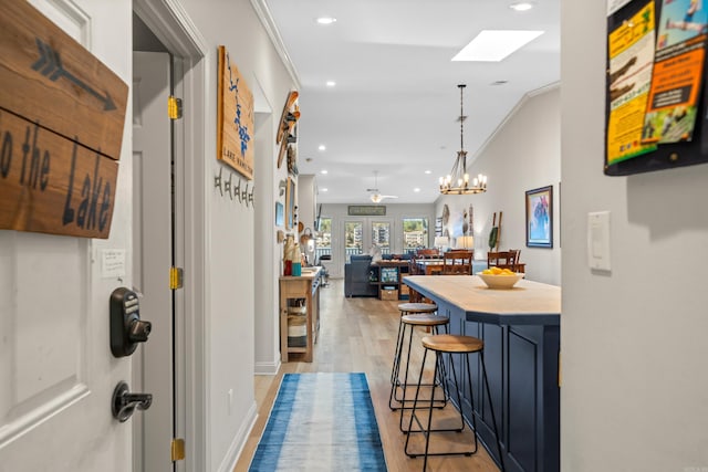 interior space with light wood-type flooring, crown molding, a chandelier, and a skylight