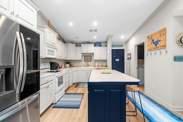 kitchen featuring white appliances, a kitchen island, a kitchen bar, tile counters, and light hardwood / wood-style floors