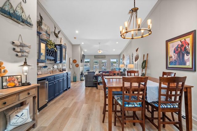 dining area featuring light hardwood / wood-style flooring, sink, ceiling fan with notable chandelier, and crown molding