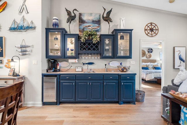 bar featuring beverage cooler, blue cabinets, light wood-type flooring, and crown molding