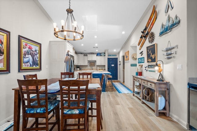 dining room with ornamental molding, light wood-type flooring, and a notable chandelier