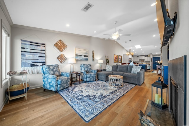 living room with hardwood / wood-style flooring, ceiling fan with notable chandelier, plenty of natural light, and crown molding