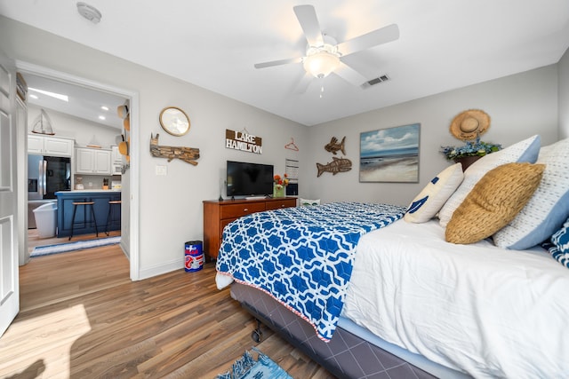 bedroom featuring stainless steel fridge, vaulted ceiling, ceiling fan, and hardwood / wood-style flooring