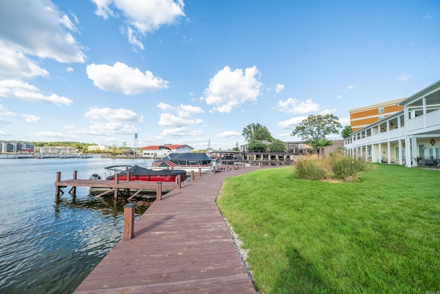 view of dock with a lawn, a water view, and a balcony