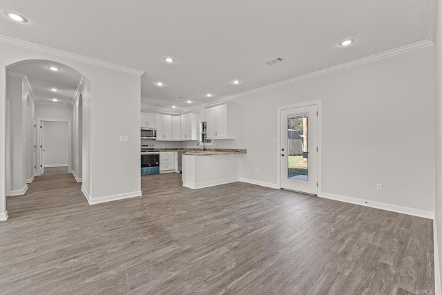 kitchen with appliances with stainless steel finishes, white cabinets, kitchen peninsula, crown molding, and light hardwood / wood-style flooring