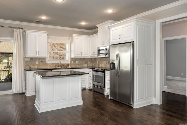 kitchen with appliances with stainless steel finishes, a center island, sink, and white cabinetry