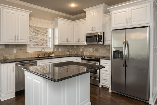 kitchen with appliances with stainless steel finishes, a kitchen island, sink, and white cabinets