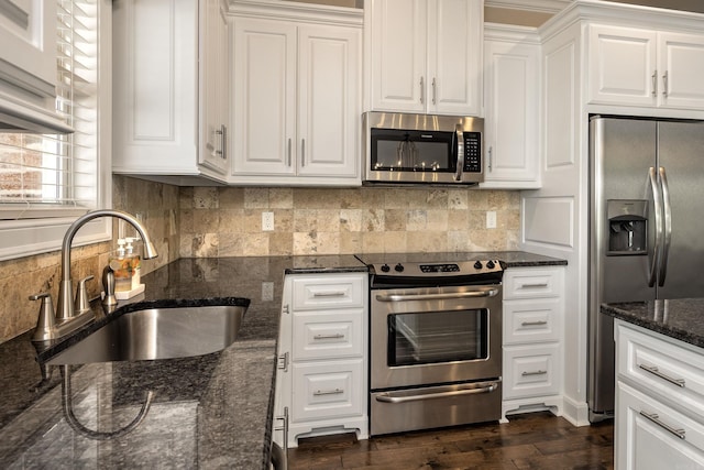 kitchen with dark stone counters, white cabinetry, sink, and stainless steel appliances