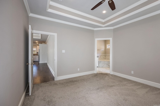 unfurnished bedroom featuring ceiling fan, dark colored carpet, a raised ceiling, and ornamental molding