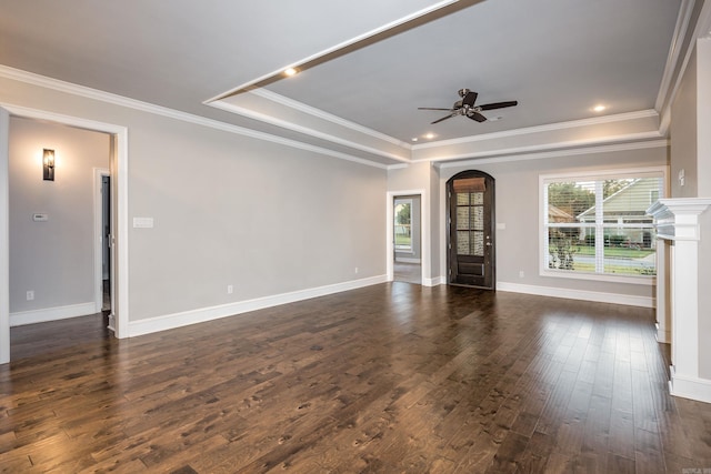 unfurnished living room with ceiling fan, ornamental molding, a tray ceiling, and dark wood-type flooring