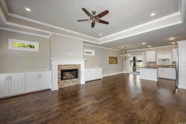 unfurnished living room with a tray ceiling, dark hardwood / wood-style floors, and a stone fireplace