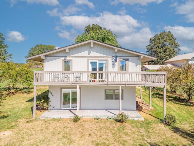 back of property featuring a yard, a wooden deck, and a patio area