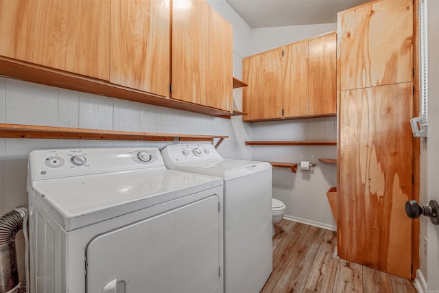 laundry area with washing machine and clothes dryer, light wood-type flooring, and a textured ceiling