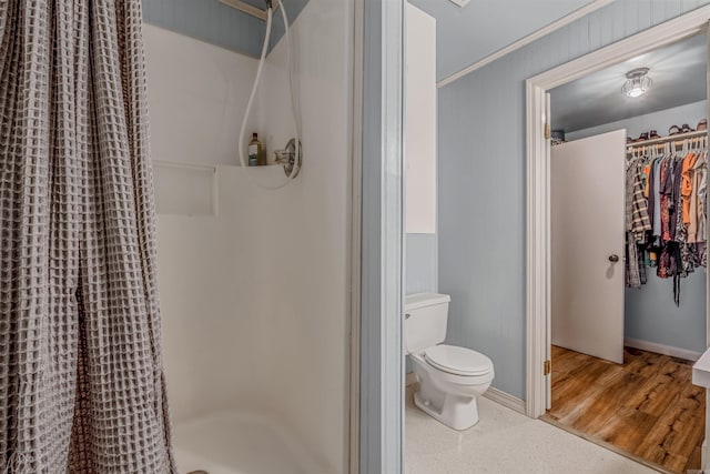 bathroom with a shower with shower curtain, crown molding, hardwood / wood-style floors, and toilet