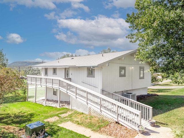 back of property with central AC, a deck with mountain view, and a yard